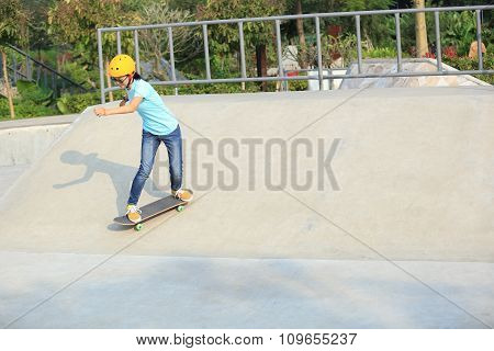 young woman skateboarder skateboarding at skatepark