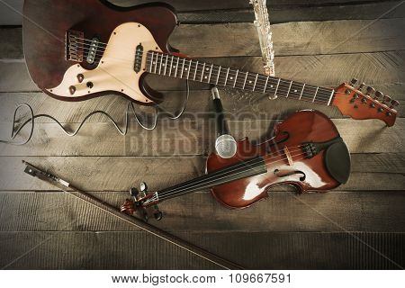 Electric guitar, violin, flute and microphone on wooden background