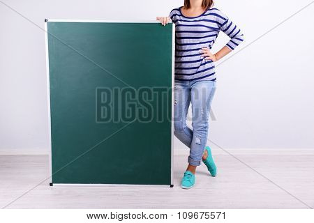 Woman in causal with green blackboard on grey background, close up