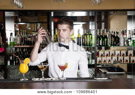 barman standing in front of the bar and making cocktail drinks