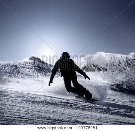 Snowboarder Silhouette Goes Down By The High Mountain Ski Slope