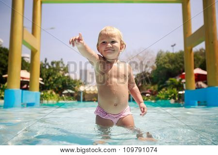 Closeup Small Blonde Girl Stands In Pool Water Points Towards