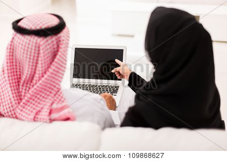 back view of muslim couple pointing at laptop screen
