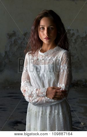 Antique edwardian lace dress worn by a beautiful woman against an old wall