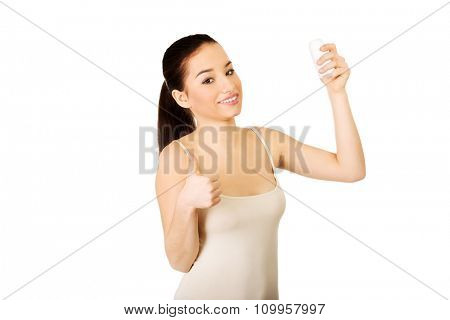 Young smiling woman with anti perspirant and thumbs up.