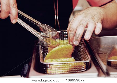 Chef is cooking chicken nuggets in a deep fryer