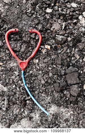 Plastic toy stethoscope on burned ground