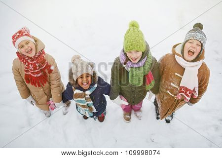 Joyful kids standing in snowdrift and looking at camera