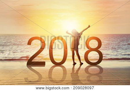 Happy new year card 2018.Silhouette of joyful young Asian girl hold hands breath fresh air on tropical beach with sunset or sunrise sky background. Happy kid watch rising sun stand in number 2018.