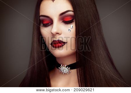 Halloween Vampire Woman portrait. Beautiful Glamour Fashion Sexy Vampire Lady with long dark Hair beauty make up and Costume