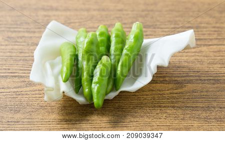 Vegetable Raw Green Hot Chili or Chilli Cayenne Pepper on Cabbage Leaf.