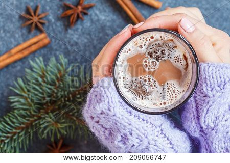 Christmas cup of cocoa in the hands of women on a background of Christmas decorations.