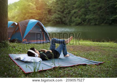 Holiday camping - Young boy resting on pallet near a tent in the forest