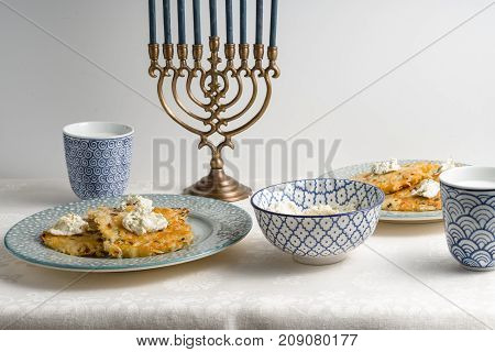 Latkes on a plate, Hanukkah, cups with milk on a white tablecloth horizontal