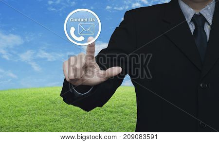 Businessman pressing telephone and mail icon button over green grass field with blue sky Contact us concept