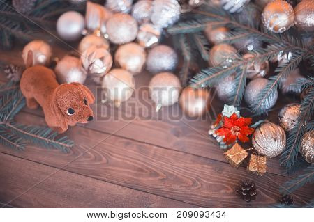 Year of the dog. Dog with a gift on a wooden background. Christmas balls pine cones a composition of the new year in golden color. The year of the dog on a horoscope symbol. Copyspace emptu space for text toned photo.