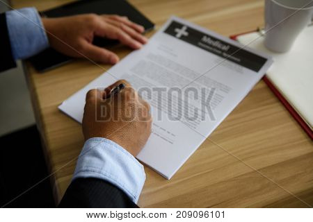 Closeup hands of Businessman CEO or Senior manager Signing Medical Contract Paper by Pen on wooden table in office. Business approach and achievement concept.