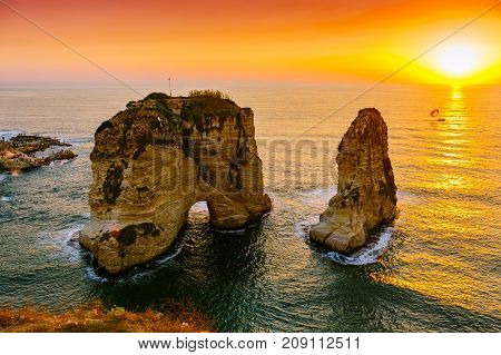 Beautiful sunset on Raouche, Pigeons' Rock. In Beirut, Lebanon.Sun and Stones are reflected in water.dense clouds in the sky.