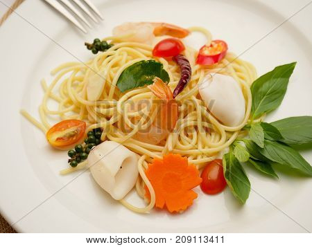Spaghetti stir fried. It has a spicy taste with shrimp and squid in white plate.