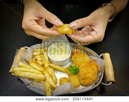 The woman eating delicious meal. There are french fries and the hot nuggets