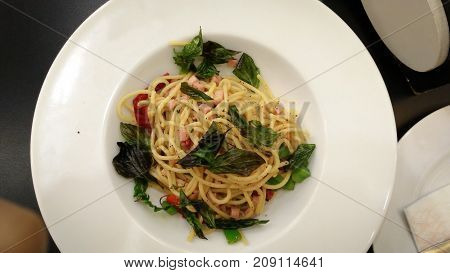Spaghetti stir fried. It has a spicy taste with ham in white plate.
