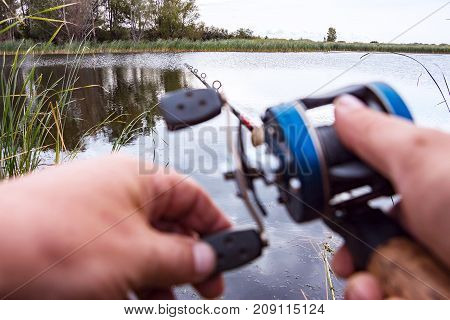 A man is fishing with a backcasting reel. Hands, a rod and a backcasting reel