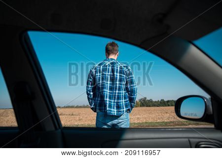 man stands on a road view from the car window