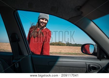woman in hat opening car door on highway