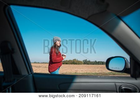 woman in hat opening car door on highway