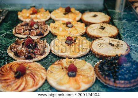Savory various fruit date pear peach and blackberry tartelette desserts displayed in a French patisserie vitrine