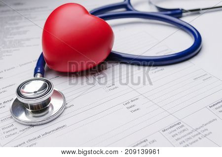 close up of red heart stethoscope and medical form on desk heart attack heart disease medical diagnosis medical report record and history patient concept selective soft focus