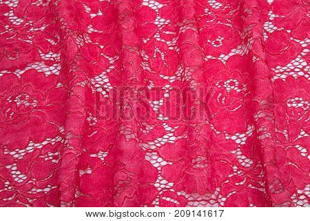 bright crimson, red guipure folds spread out on a white table