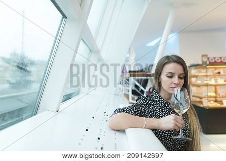 Beautiful woman enjoying wine while relaxing in a retsora with a dazzling light interior. The rest of the woman with wine.