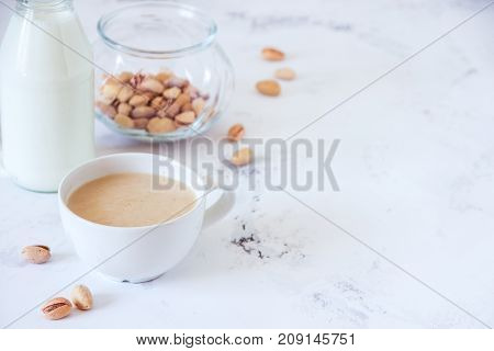 Coffee With Milk And Pistachios On Wooden Table, Copy Space
