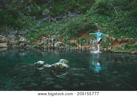 a woman tourist stands on the Bank of the mountain lake with turquoise water. Glanni waterfall, Iceland, woman tries to go into cold water