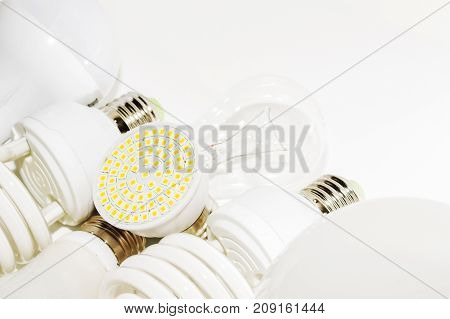 Several different led bulbs and compact fluorescent lamps with the size of the male screw base E27 on a light background