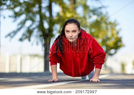 Lovely girl in red uniform girl squeezes off the floor in the street