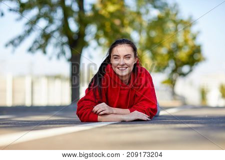 Beautiful girl in a red uniform the girl is lying on her stomach from on the street