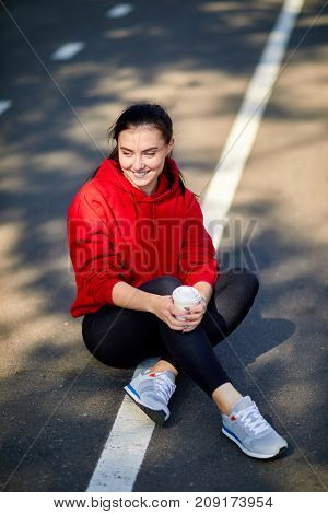 Young beautiful girl sits on the ground in a red uniform on a sunny autumn day