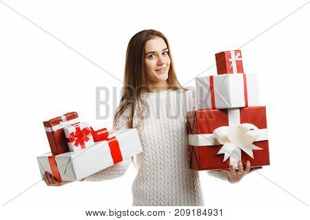 Pretty cutie girl with a long hair posing on the camera in studio and holding christmas gift isolated on white background. Close-up of gifts. Holiday concept.
