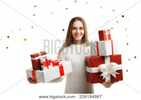 Pretty cutie girl with a long hair posing on the camera in studio and holding christmas gift isolated on white background. Close-up of gifts. Holiday concept.