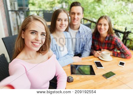 Friends who have fun in a cafe. Do selfie. Concept of leisure.