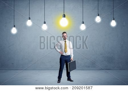 Handsome businessman in an empty space with bulbs above and uninspired face
