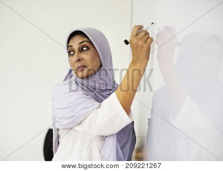 Muslim teacher writing on a white board