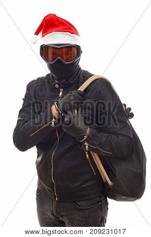 Masked burglar with santa claus cap holding his sack posing on isolated background