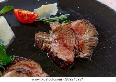 Traditional Italian Tagliata Steak with Parmesan and Salad as close-up on a plate