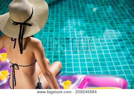 Women wearing bigini or swimware suits swimming pool sitting on a blue protrude at the resort town of Pattaya in Thailand.