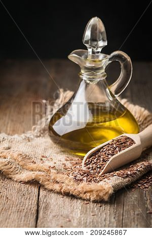 flax seeds and linseed oil in a glass jug on a wooden table, healthy diet with omega 3 fatty acids
