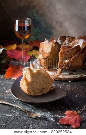 Bundt cake with saffron and rum covered with white glaze on rustic background with autumn decorations