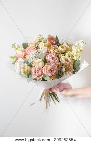 Mix flowers. Luxury bouquets in the girl's hands. on a light gray wall